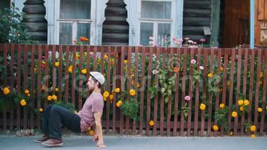 一个男人在村子里用鲜花在篱笆旁跳俄罗斯民族舞蹈